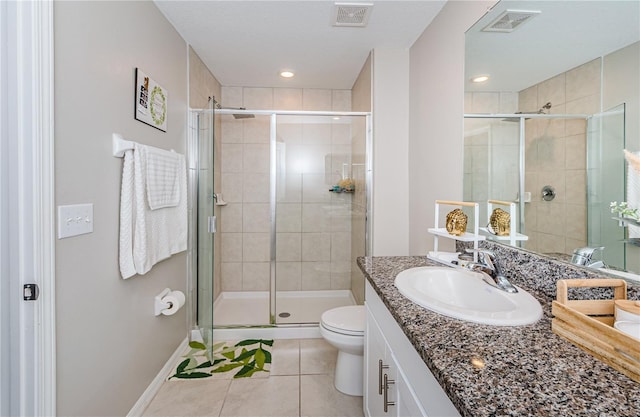 bathroom featuring toilet, vanity, tile patterned floors, and a shower with shower door