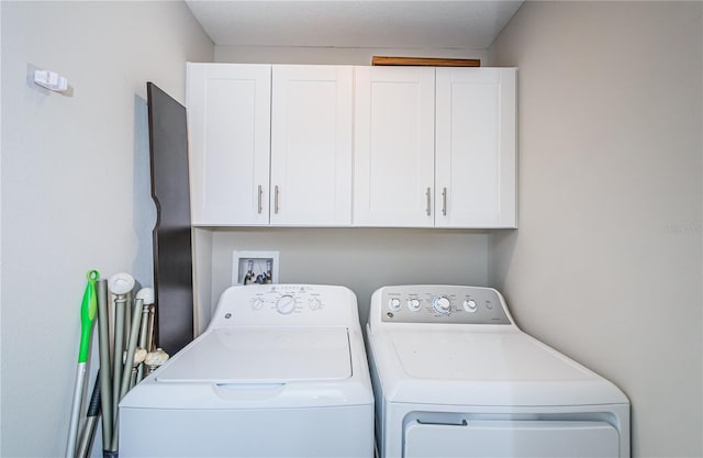 laundry area with washing machine and clothes dryer and cabinets