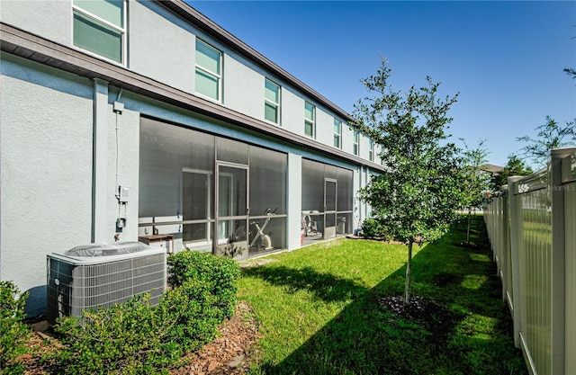 back of house with a sunroom, a yard, and central AC