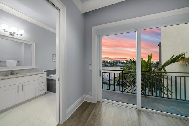 entryway featuring light tile patterned flooring, sink, and a water view