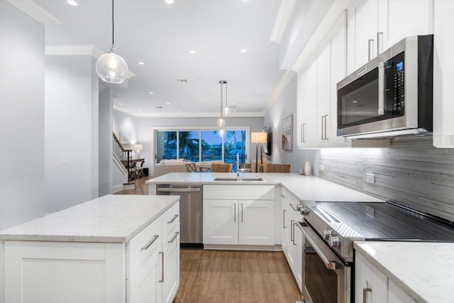 kitchen with tasteful backsplash, white cabinets, light wood-type flooring, crown molding, and appliances with stainless steel finishes