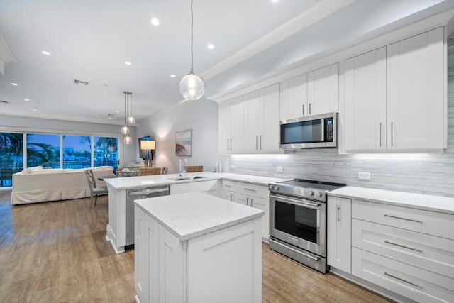 kitchen featuring light wood-type flooring, kitchen peninsula, backsplash, stainless steel appliances, and sink