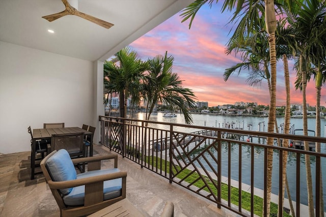 balcony at dusk featuring a water view