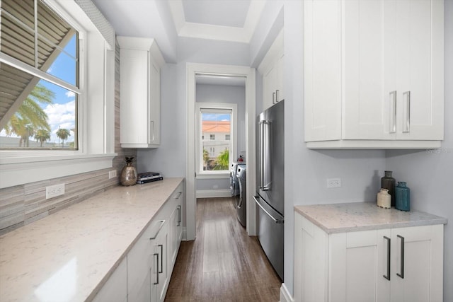 kitchen featuring white cabinetry, independent washer and dryer, dark hardwood / wood-style flooring, light stone counters, and high end fridge