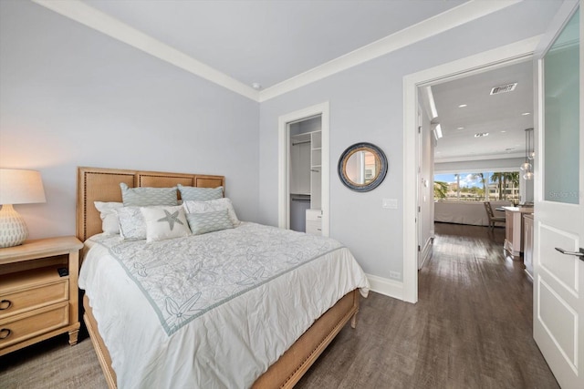 bedroom with a spacious closet, dark hardwood / wood-style floors, a closet, and ornamental molding