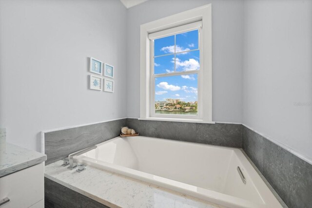 bathroom with tiled tub and vanity