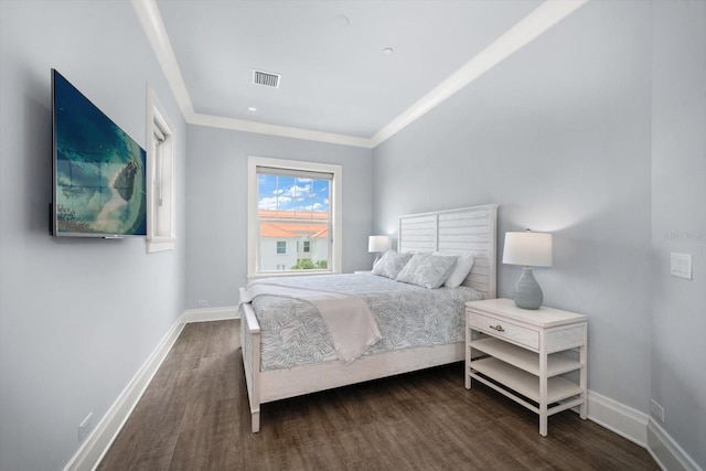 bedroom with ornamental molding and dark hardwood / wood-style floors