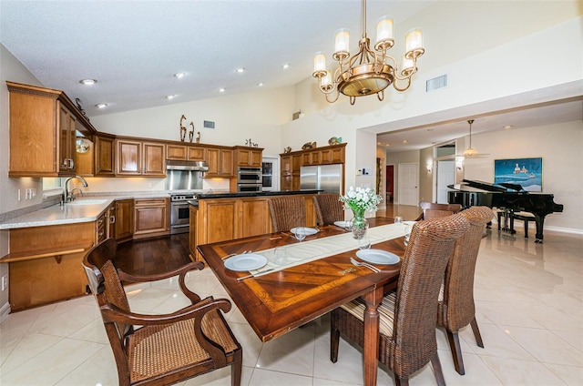 dining area with light tile patterned flooring, high vaulted ceiling, sink, and a notable chandelier