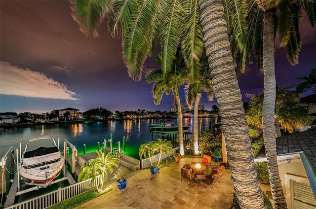 patio terrace at dusk with a dock and a water view