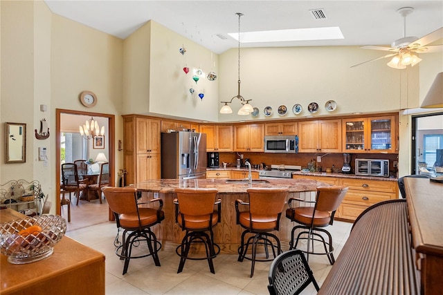 kitchen with sink, a skylight, high vaulted ceiling, appliances with stainless steel finishes, and a kitchen breakfast bar