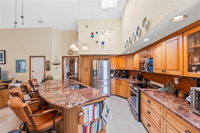 kitchen featuring light tile patterned flooring, appliances with stainless steel finishes, a kitchen bar, and sink