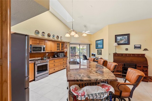 kitchen featuring pendant lighting, sink, a skylight, stainless steel appliances, and light tile patterned flooring