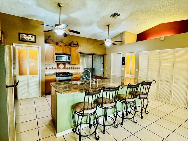 kitchen with sink, backsplash, vaulted ceiling, a kitchen bar, and appliances with stainless steel finishes