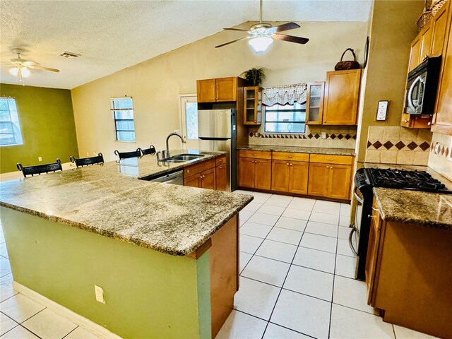 kitchen with appliances with stainless steel finishes, tasteful backsplash, a spacious island, and sink