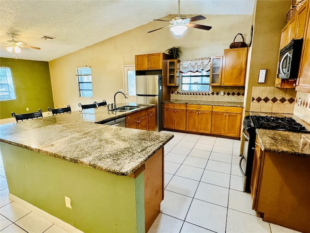 kitchen with sink, stainless steel appliances, a large island with sink, and a kitchen bar