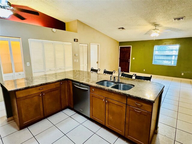 kitchen with dishwasher, lofted ceiling, sink, a textured ceiling, and light tile patterned flooring