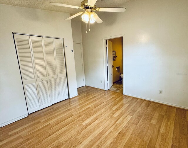 unfurnished bedroom with ensuite bath, light hardwood / wood-style flooring, ceiling fan, a textured ceiling, and a closet