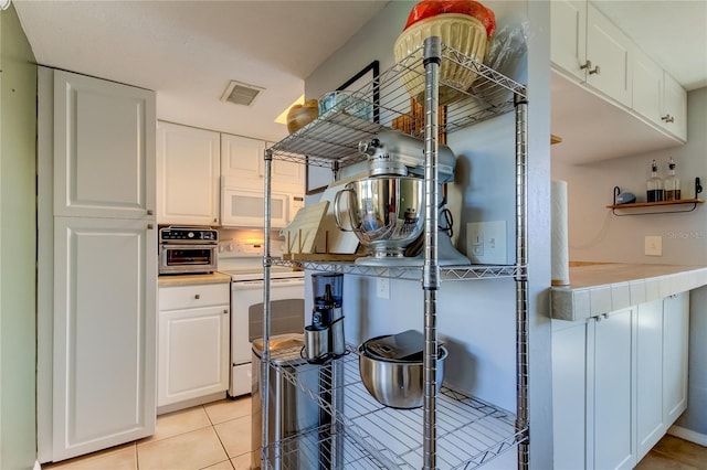 kitchen featuring white cabinets, light tile patterned floors, and white appliances