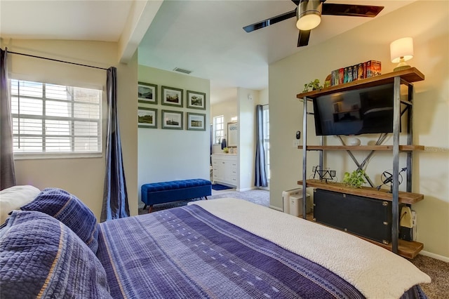 carpeted bedroom featuring vaulted ceiling, ensuite bath, and ceiling fan