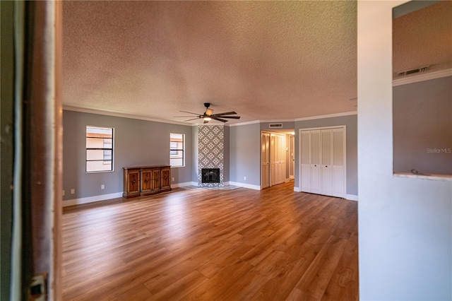 unfurnished living room with hardwood / wood-style flooring, a fireplace, ceiling fan, and crown molding