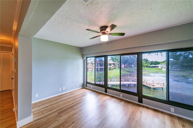 unfurnished room featuring ceiling fan, plenty of natural light, a textured ceiling, and light hardwood / wood-style flooring