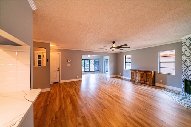 unfurnished living room featuring hardwood / wood-style flooring, ceiling fan, crown molding, and a textured ceiling