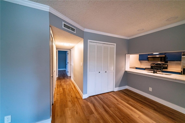 unfurnished bedroom with crown molding, sink, hardwood / wood-style flooring, a textured ceiling, and a closet