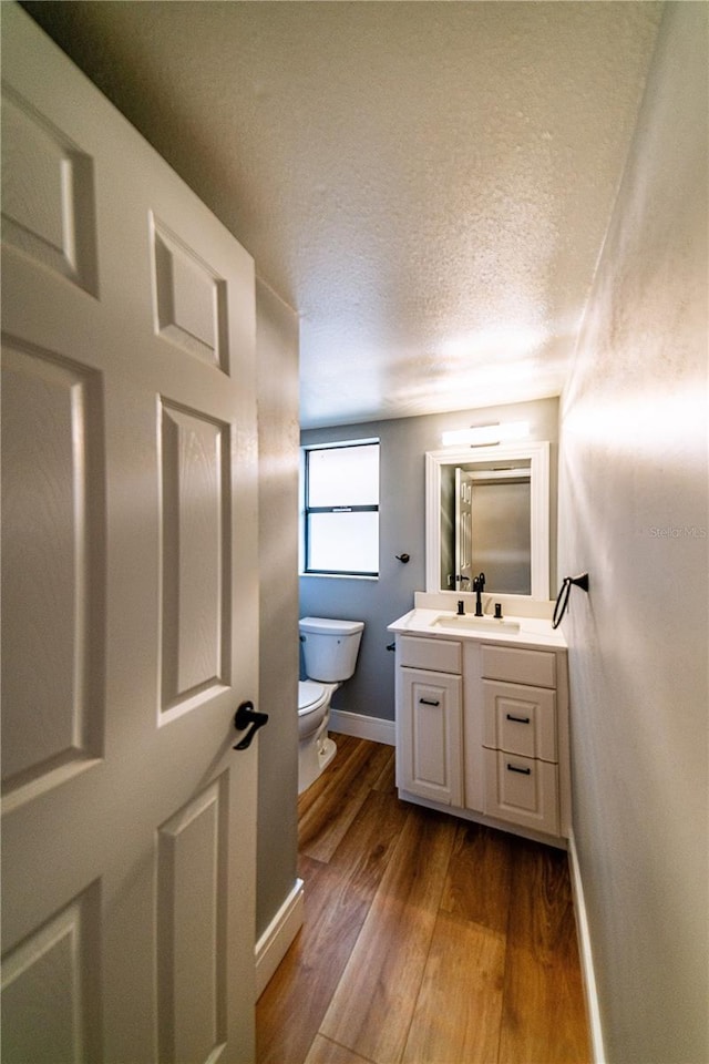 bathroom featuring hardwood / wood-style flooring, vanity, toilet, and a textured ceiling