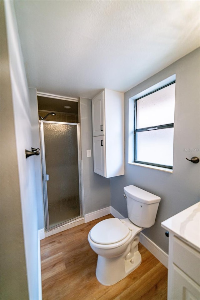 bathroom with walk in shower, toilet, vanity, and hardwood / wood-style flooring