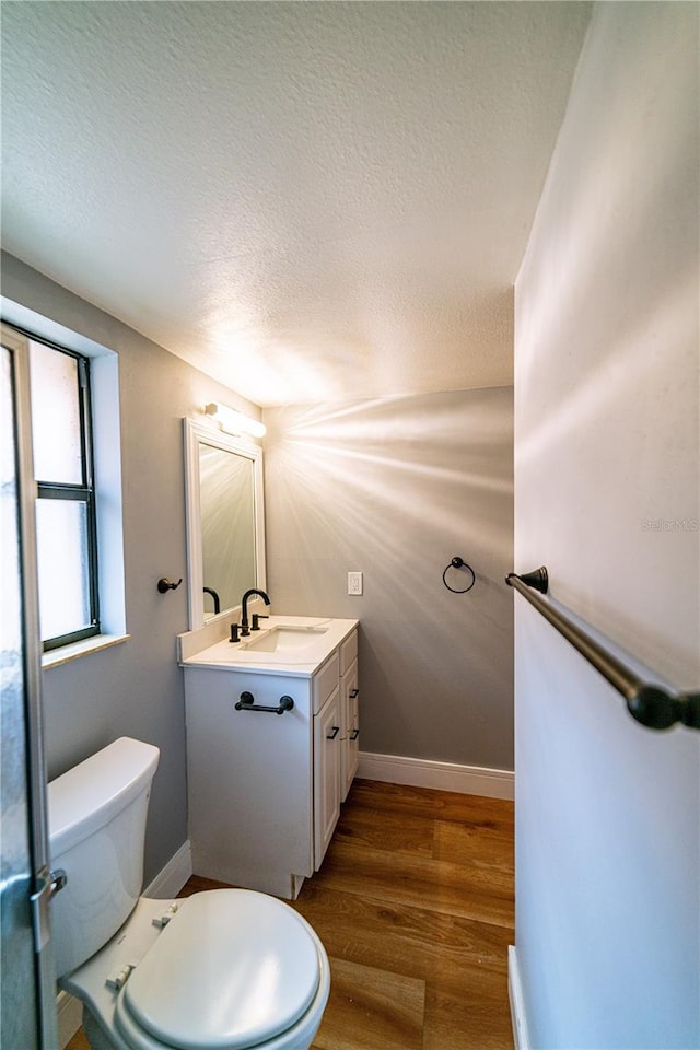 bathroom featuring hardwood / wood-style floors, vanity, toilet, and a textured ceiling