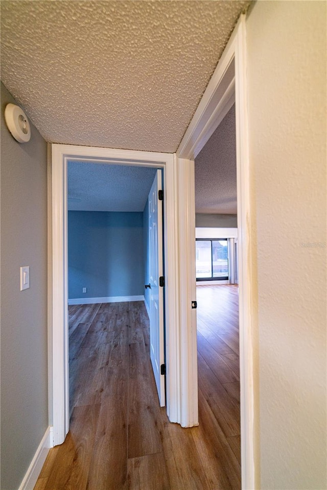 corridor featuring hardwood / wood-style floors and a textured ceiling