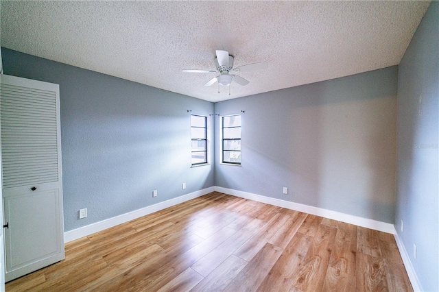 empty room with ceiling fan, light wood-type flooring, and a textured ceiling