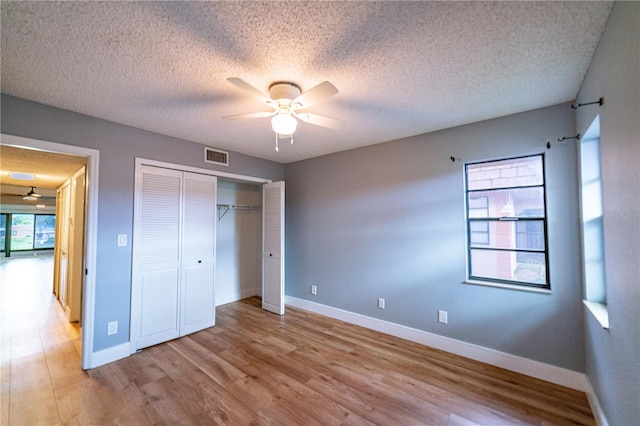 unfurnished bedroom featuring ceiling fan, a closet, light hardwood / wood-style floors, and a textured ceiling