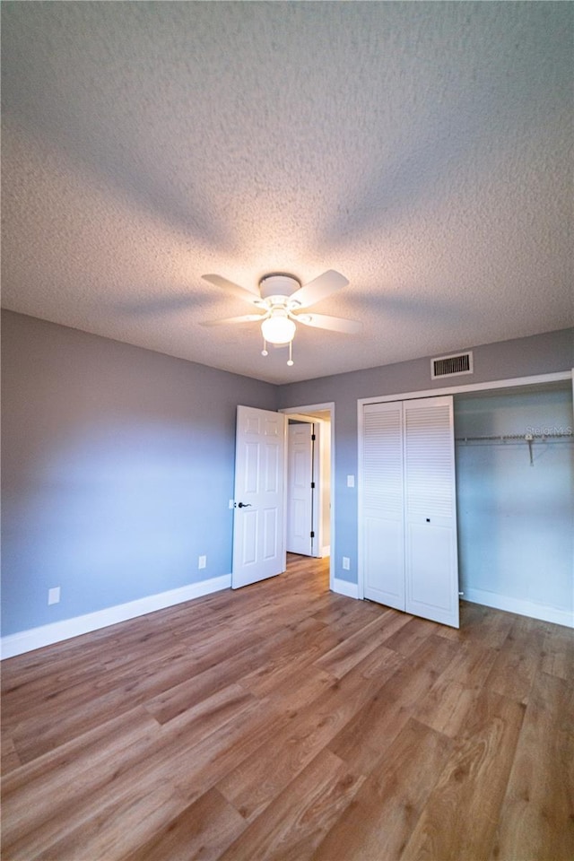 unfurnished bedroom featuring ceiling fan, a closet, a textured ceiling, and light hardwood / wood-style flooring