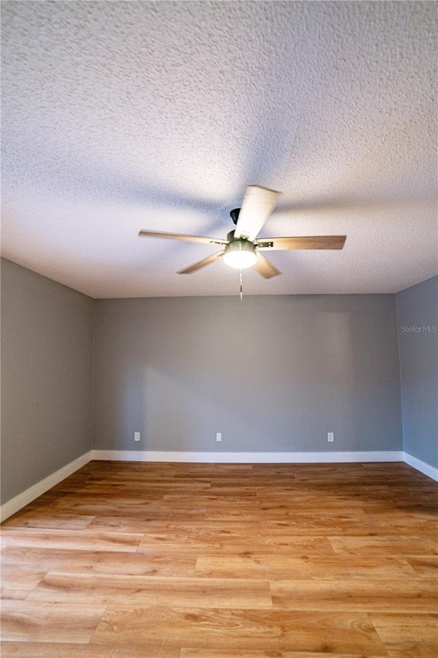 empty room with ceiling fan, light wood-type flooring, and a textured ceiling