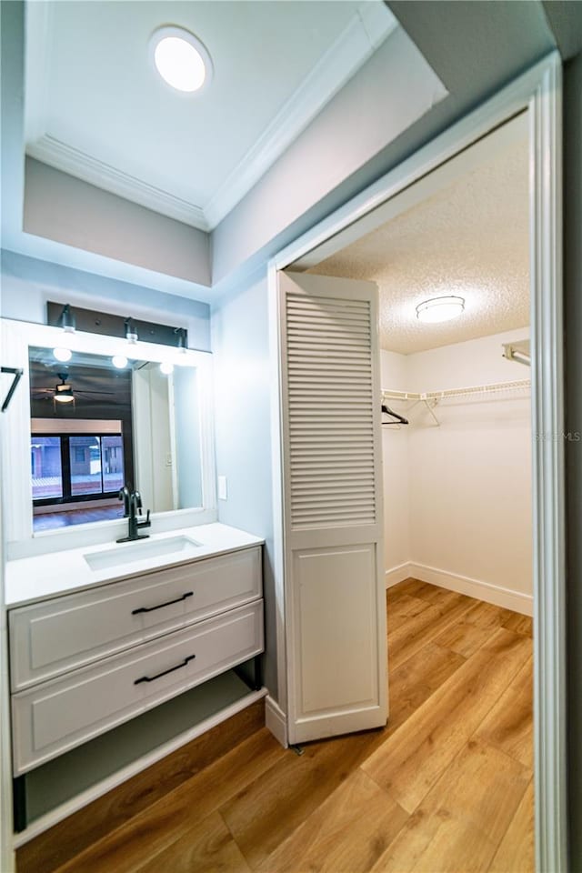 interior space with wood-type flooring, vanity, a textured ceiling, and ornamental molding