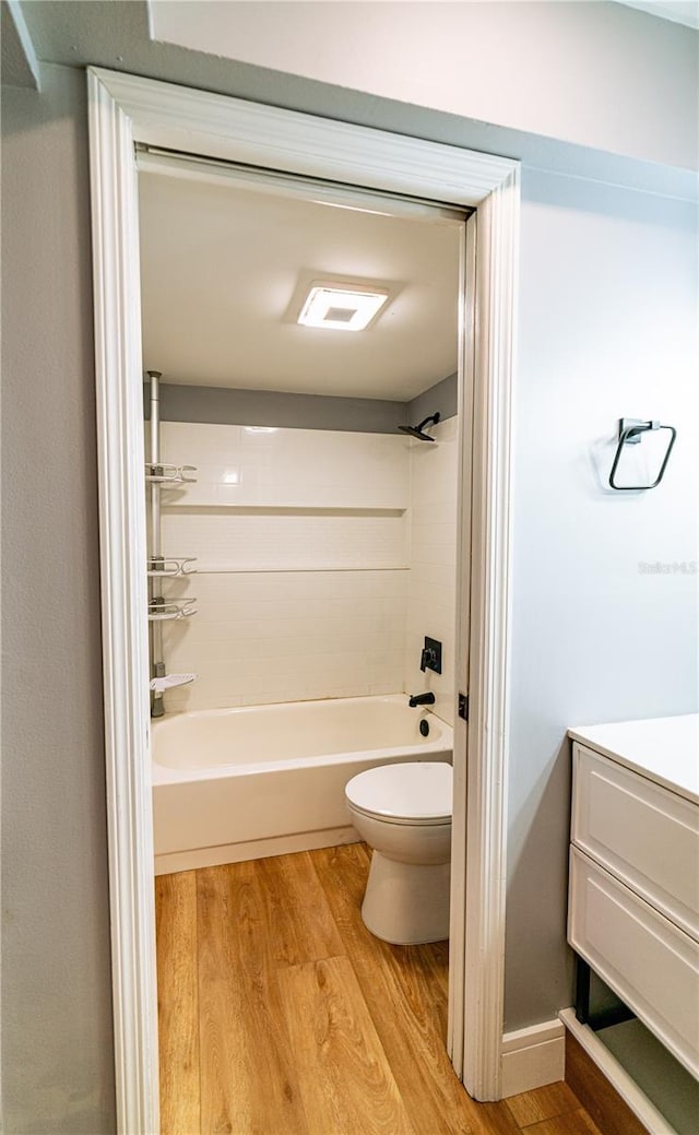 full bathroom with hardwood / wood-style floors, vanity, shower / bathtub combination, and toilet