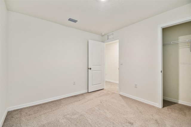 unfurnished bedroom with light colored carpet and a closet