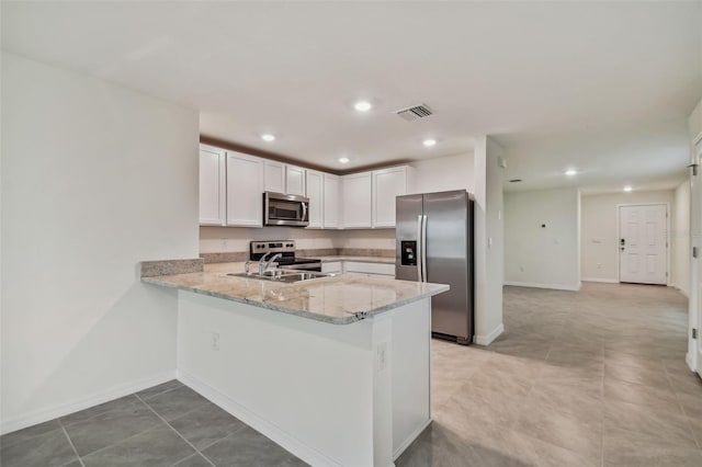 kitchen featuring white cabinets, sink, appliances with stainless steel finishes, light stone counters, and kitchen peninsula