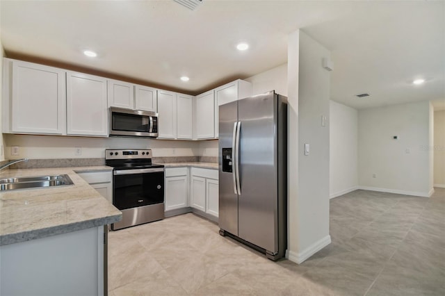 kitchen featuring light stone counters, white cabinetry, sink, and appliances with stainless steel finishes