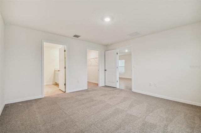 5552 Logan Cave Ave, Wimauma, FL 33598 - unfurnished bedroom with light carpet, visible vents, and a walk in closet