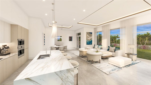 interior space featuring light stone countertops, pendant lighting, a kitchen island with sink, and sink