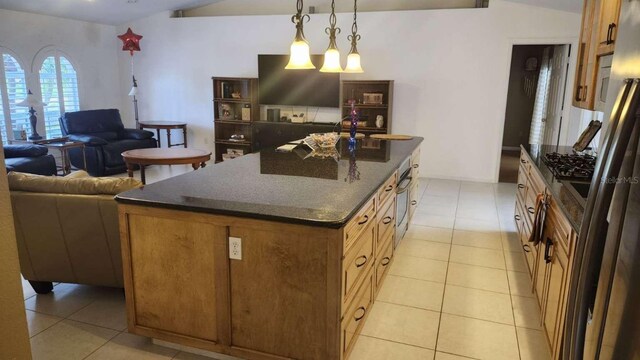 kitchen with lofted ceiling, dark stone countertops, light tile patterned floors, a kitchen island, and hanging light fixtures