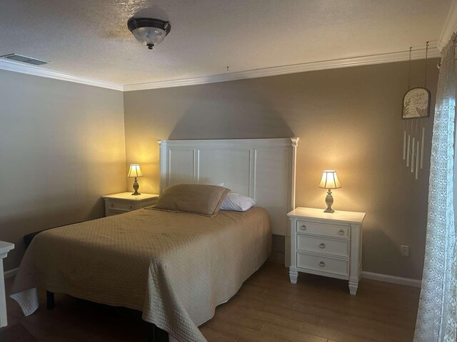 bedroom featuring wood-type flooring, a textured ceiling, and ornamental molding