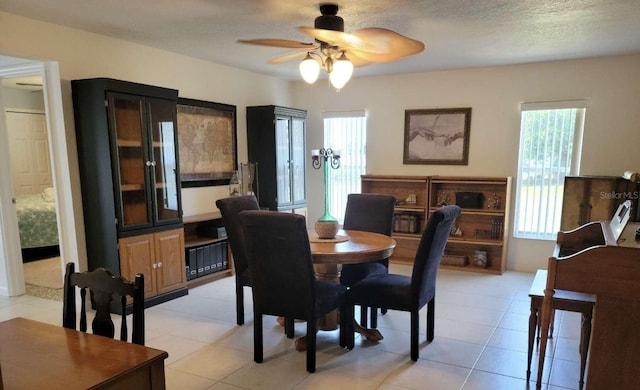 tiled dining space with a textured ceiling and ceiling fan