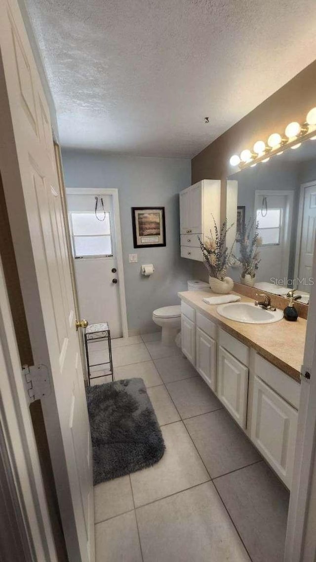 bathroom with tile patterned flooring, toilet, vanity, and a textured ceiling