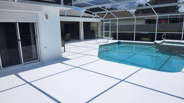 view of pool with an in ground hot tub, glass enclosure, and a patio area