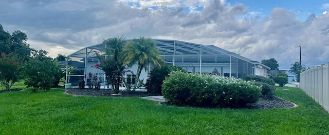 view of side of property featuring a lawn and glass enclosure