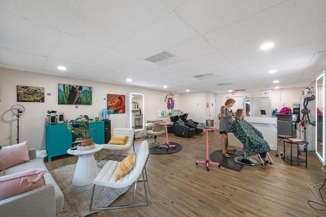 interior space with a drop ceiling and wood-type flooring