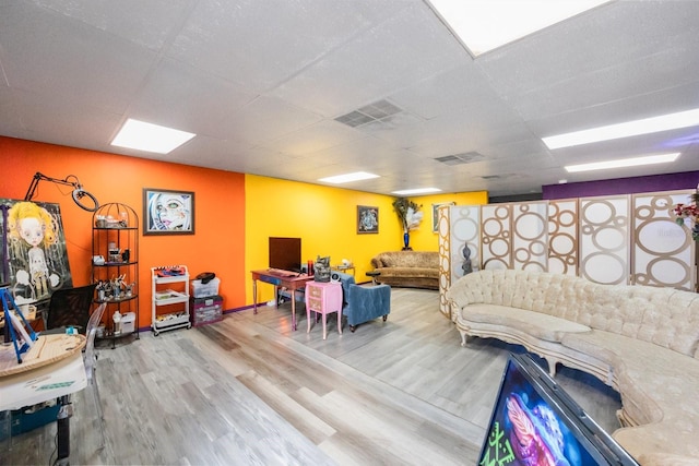 living room with a drop ceiling and light wood-type flooring